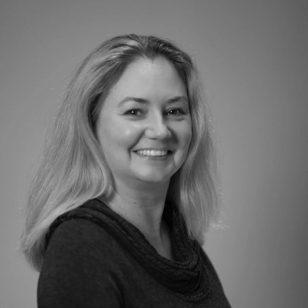 Smiling woman with long hair in a black and white portrait.