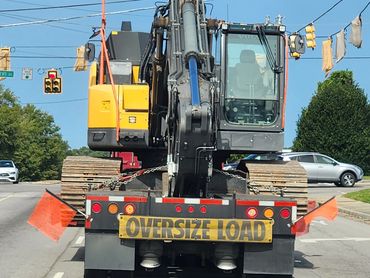 Heavy construction equipment being transported with oversize load sign.