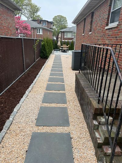 Neatly arranged stepping stones on a gravel path beside a brick house.