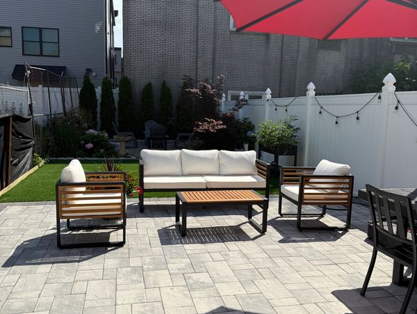 Modern outdoor patio with white cushioned furniture and a large red umbrella.