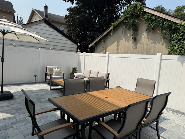 Modern outdoor patio with wooden dining set and cushioned seating area under a large umbrella.