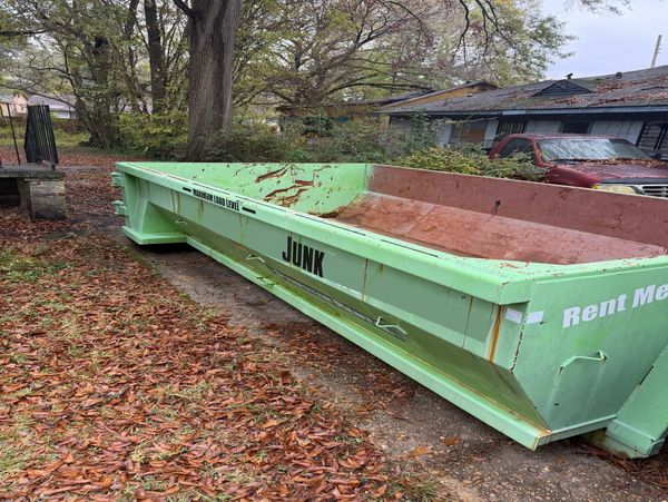 Trash out on an investment property picturing a large green dumpster outside of a home..