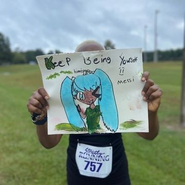 holding a sign that says keep being yourself