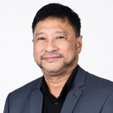 Smiling man in a dark blazer against a white background.