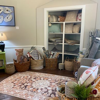 Cozy corner with baskets of rugs and cushions, and a patterned carpet on wooden floor.