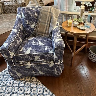 Cozy armchair with sailboat print and plaid throw in a warm, inviting living room.