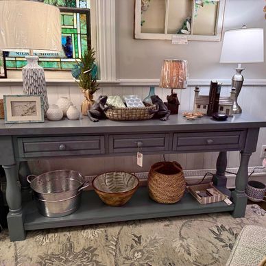 Decorative console table with lamps, baskets, and small ornaments in a cozy room.