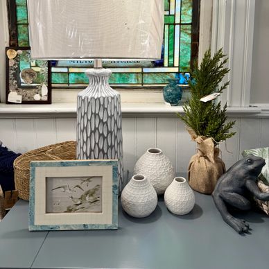 Decorative table setup with a lamp, vases, framed art, and a frog sculpture.