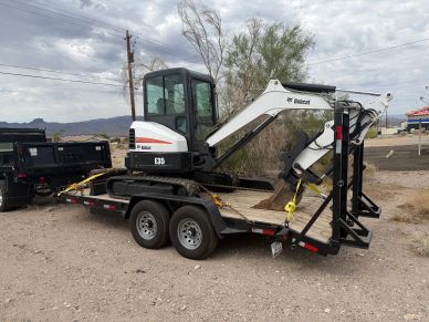 Bobcat E35 mini excavator loaded on a trailer in a desert area.