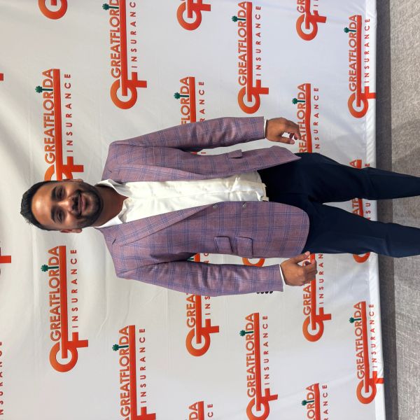 Lazim in blazer standing in front of Great Florida Insurance backdrop.
