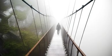 A person crossing a bridge into the foggy unknown.
