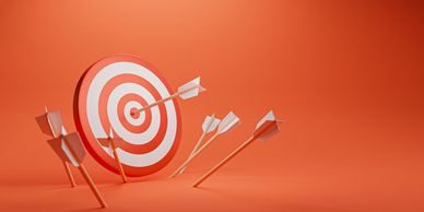 Photo of a target with arrows, one that has hit the bullseye, on a red background.