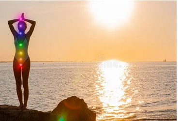 A lady balancing her chakras near the ocean spiritually exposing her body to be cleansed