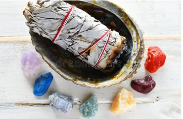 A clearing by done with sage lit up in a type of bowl with crystals around it on top of a table