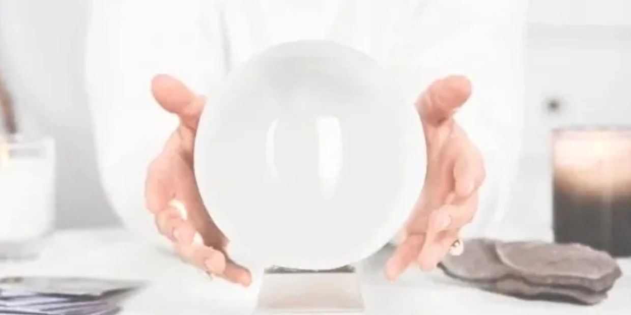 A persons hands around a white crystal ball