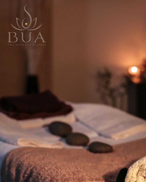 Massagebett mit heißen Steinen und gedämpfter Beleuchtung.