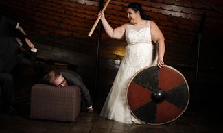 Funny bridal portrait of best man off to the left, groom with head on stool and axe wielding bride.