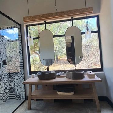 Modern bathroom with dual stone sinks and large window view.