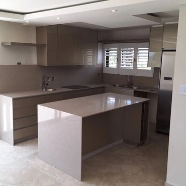 Modern kitchen with sleek beige cabinets and a polished island countertop.