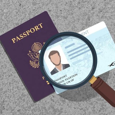 A magnifying glass examining an ID card and a passport on a gray surface.