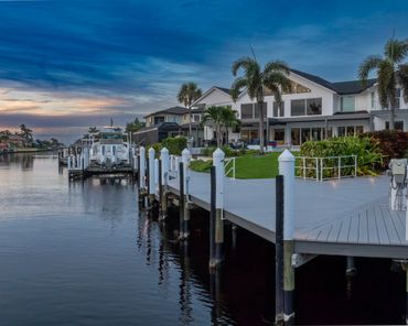 Waterfront home with dock and boats at sunset.