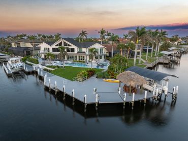 Waterfront luxury home with expansive dock and boat lift at sunset.