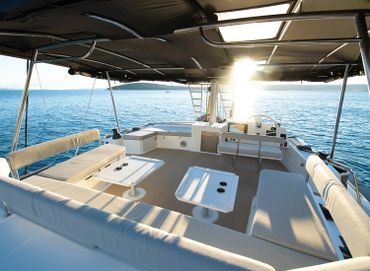 Spacious and shaded seating area on a yacht overlooking calm ocean waters.