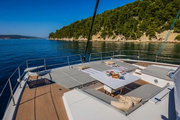 Luxurious yacht deck with food and drinks by a scenic coastline.