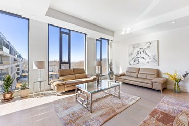 Bright modern living room with large windows and beige leather sofas.