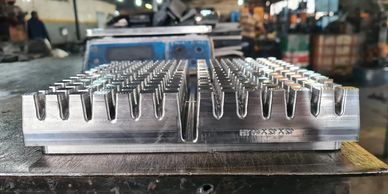 Metal mold or die with multiple cavities on a workshop table.