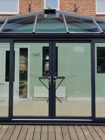 a black uPVC conservatory with double glazed windows, a glass room and a set of patio doors