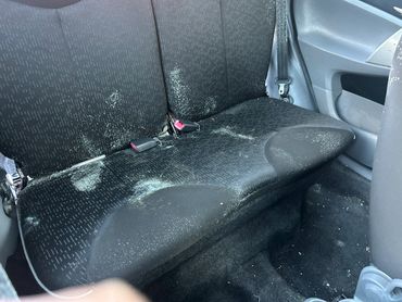 Car backseat with white powder stains and dirt marks.