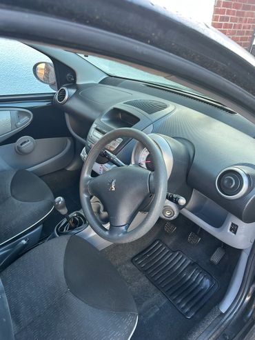 Interior of a right-hand drive Peugeot car with manual transmission.
