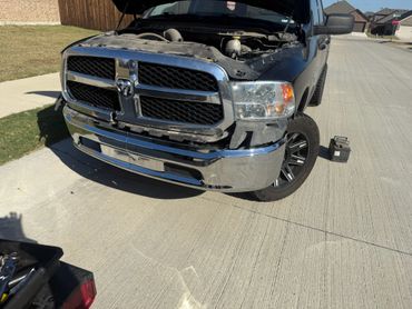 Damaged black Dodge truck during bumper repair.