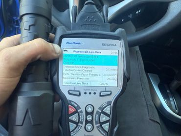 Hand holding a Blue-Point diagnostic tool inside a car.