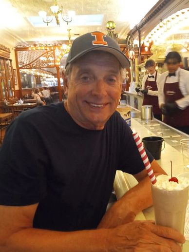 Man smiling with a milkshake in a retro diner.