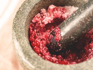 Granite mortar and pestle crushing red berries.
