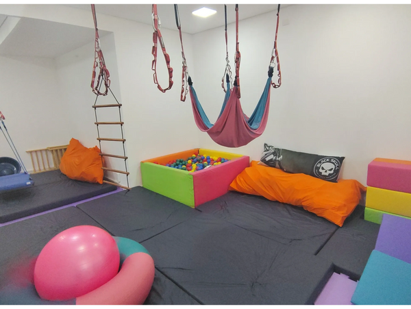 foto da ampla sala de integração sensorial, com diversos equipamentos coloridos e suspensos.