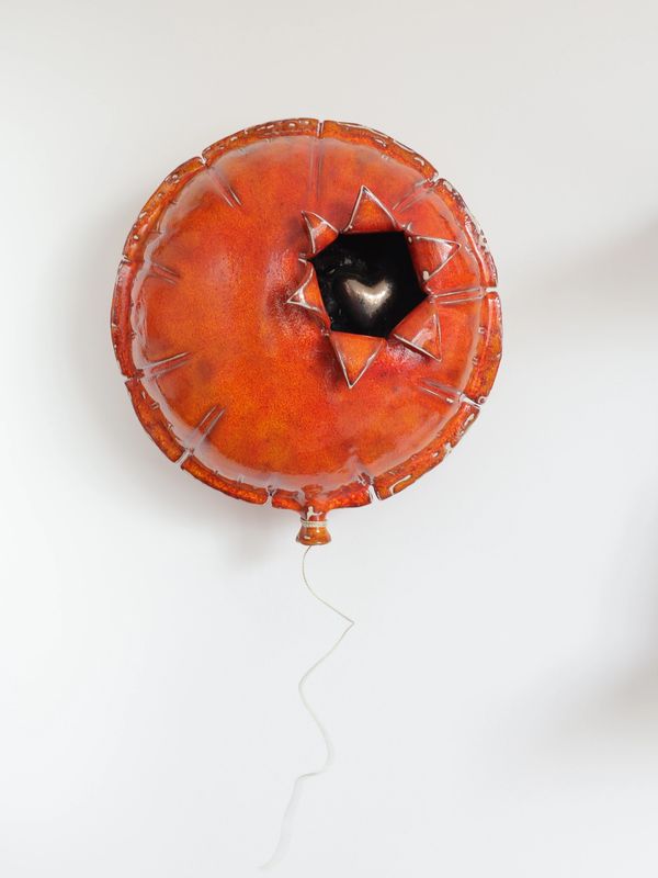 A red balloon with a jagged hole revealing a shiny heart inside.