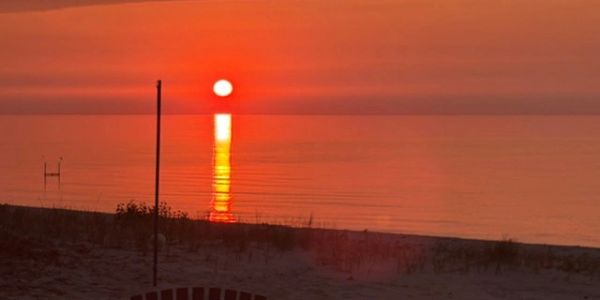 Sunset over a calm beach reflecting on the water.