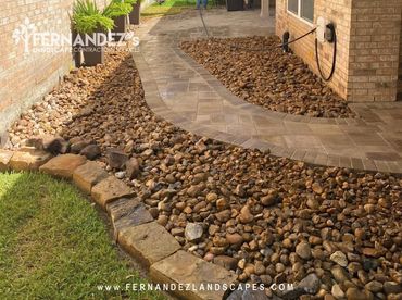 River rock bed beside a paver walkway and a stone border