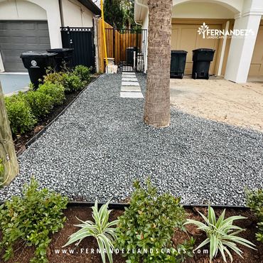 Gray gravel side yard with new plants along a driveway
