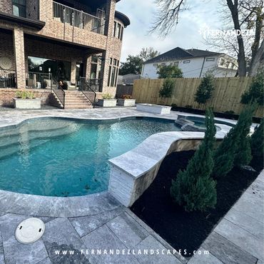 Pool with a stone deck, black mulch beds and evergreen shrubs