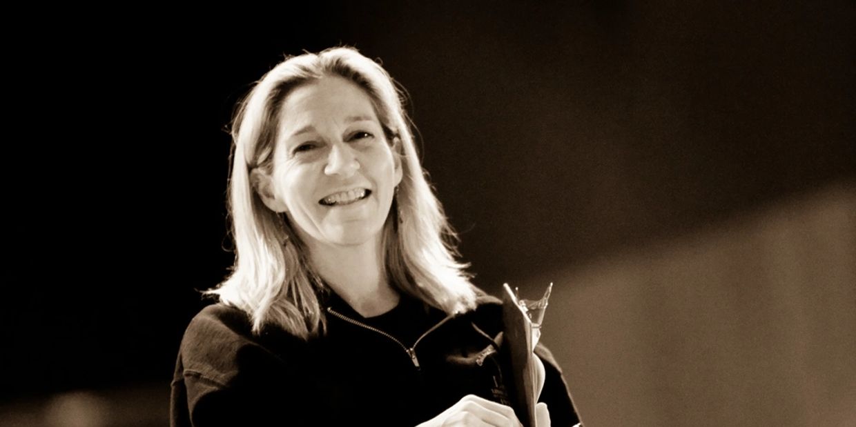 Smiling woman holding a trophy in a sepia-toned photo.