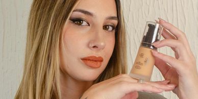 Woman showcasing a bottle of liquid foundation makeup.