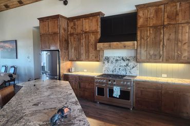 Rustic kitchen with wooden cabinets and granite countertops under warm lighting.