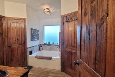 Rustic bathroom with wooden doors and a white bathtub beneath a frosted window.