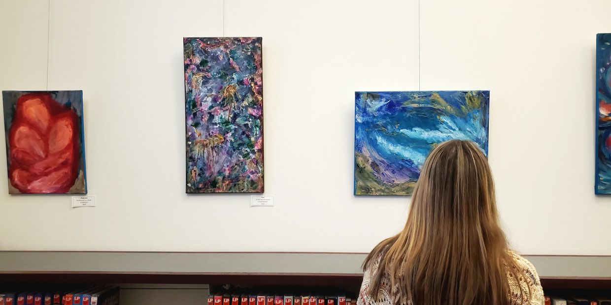 Person viewing colorful abstract paintings in a gallery.