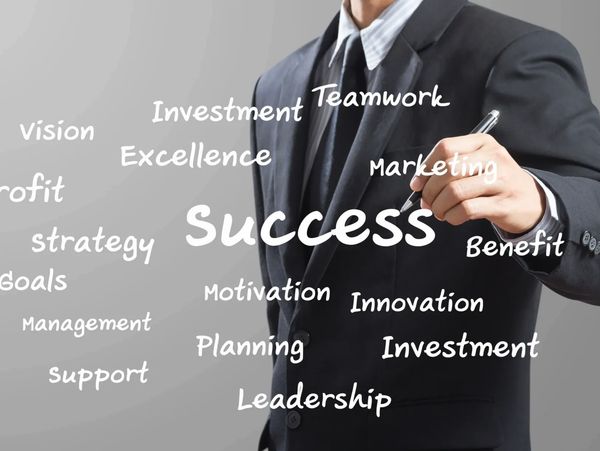 Businessman in suit writing success-related words in the air.
