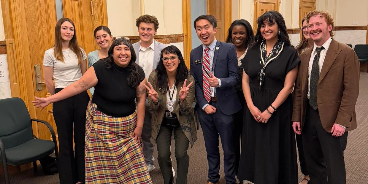 A diverse group of people smiling and posing indoors in a formal setting.